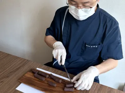 원장이 길쭉한 공진단 반죽을 작은 덩이로 자르는 모습