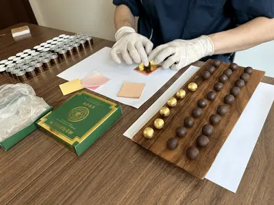 둥글게 빚은 공진단에 손으로 금박을 입히는 모습