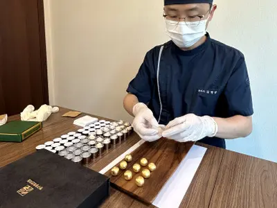 금박을 입힌 공진단을 종이로 한 알씩 감싸는 모습